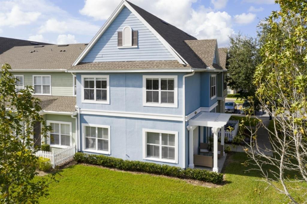An exterior view of a two-story blue townhouse with a white pergola and green lawn — 2201 SAN VITTORINO CIRCLE UNIT 108, KISSIMMEE, FL
