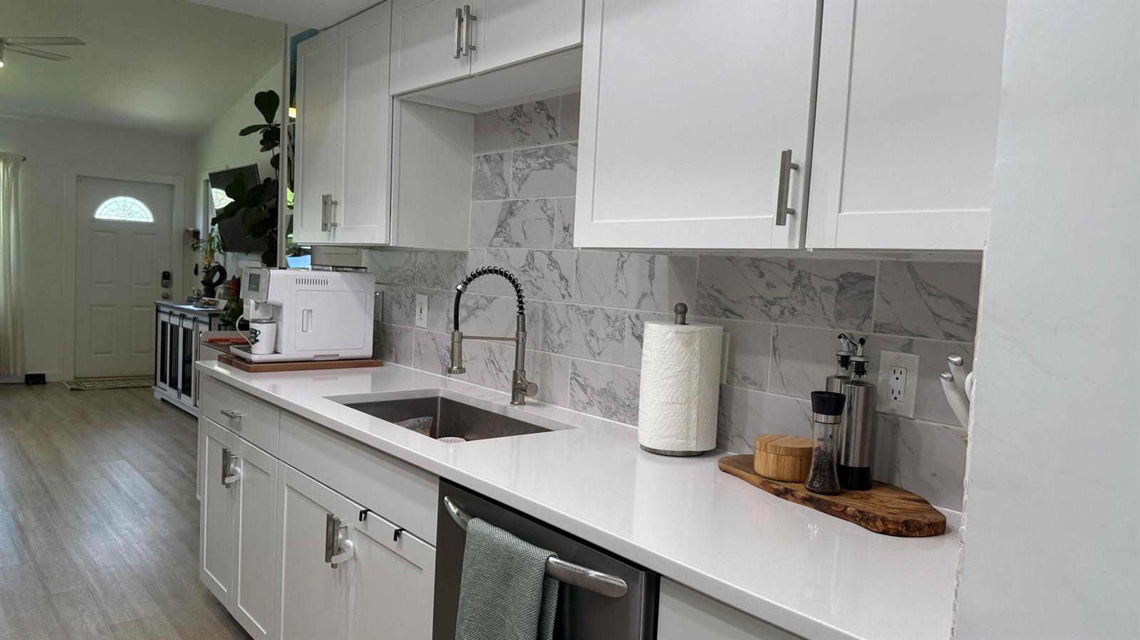 A kitchen with white cabinets, stainless steel appliances, and light wood-look flooring — 125 Doe Trail, Jupiter FL 33458, JUPITER, FL