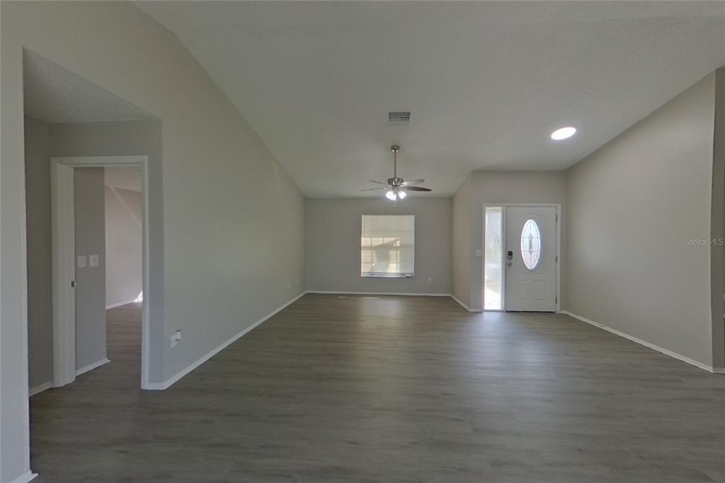 An open-concept living area features light gray walls, wood-look flooring, and a ceiling fan — 39 TROTTERS CIRCLE, KISSIMMEE, FL