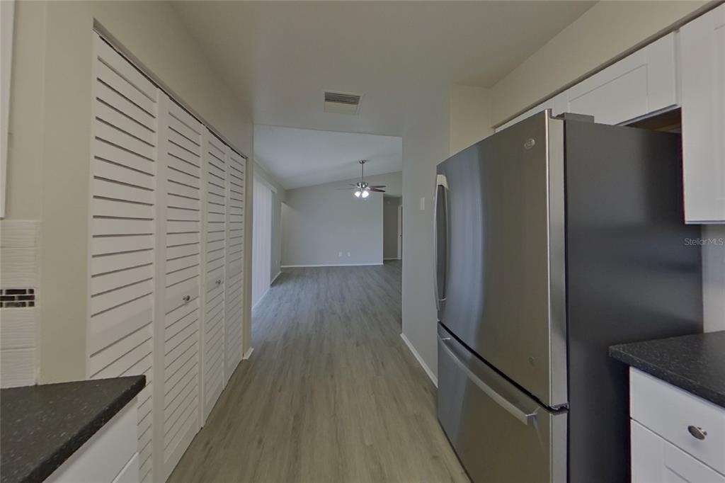 A kitchen hallway features white louvered closet doors, a stainless steel refrigerator, and wood-look flooring — 39 TROTTERS CIRCLE, KISSIMMEE, FL