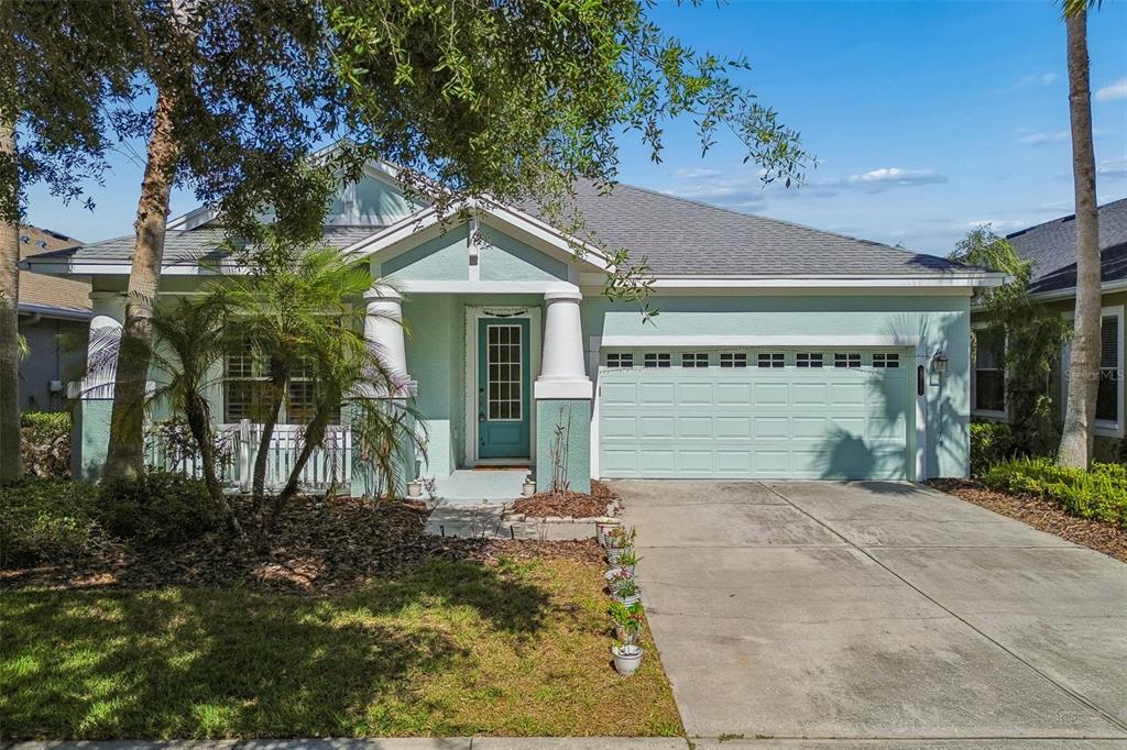 A light green single-story house with a two-car garage and a covered front entryway — 20133 HERON CROSSING DRIVE, TAMPA, FL