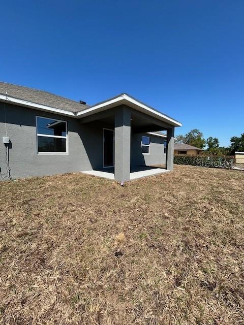 The exterior of a gray house features a covered patio and a large backyard — 7352 DONAHUE STREET, PORT CHARLOTTE, FL