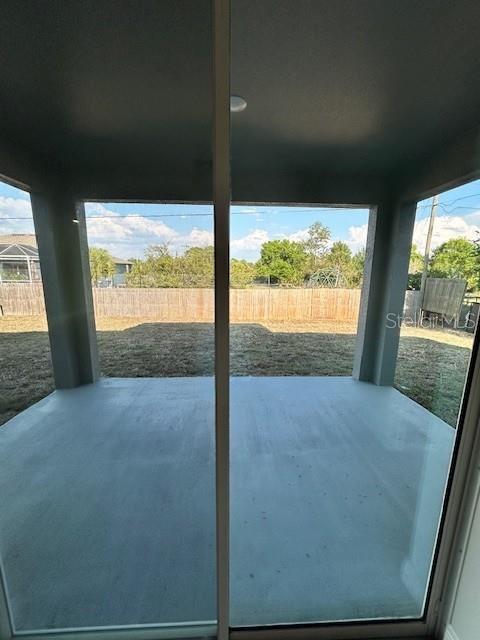 A view from inside looking out through a sliding glass door onto a concrete patio — 7352 DONAHUE STREET, PORT CHARLOTTE, FL