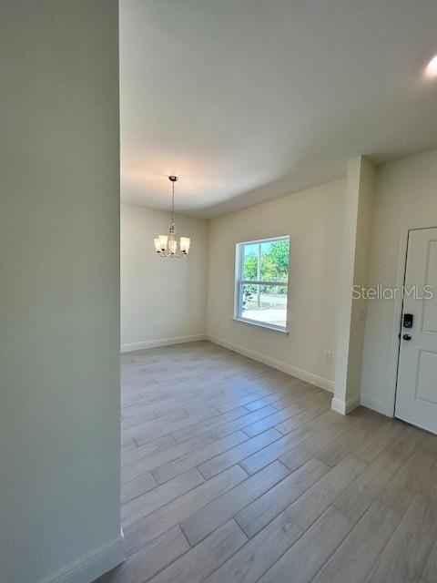 A dining area features light-colored wood-look tile flooring, a chandelier, and a single window — 7352 DONAHUE STREET, PORT CHARLOTTE, FL