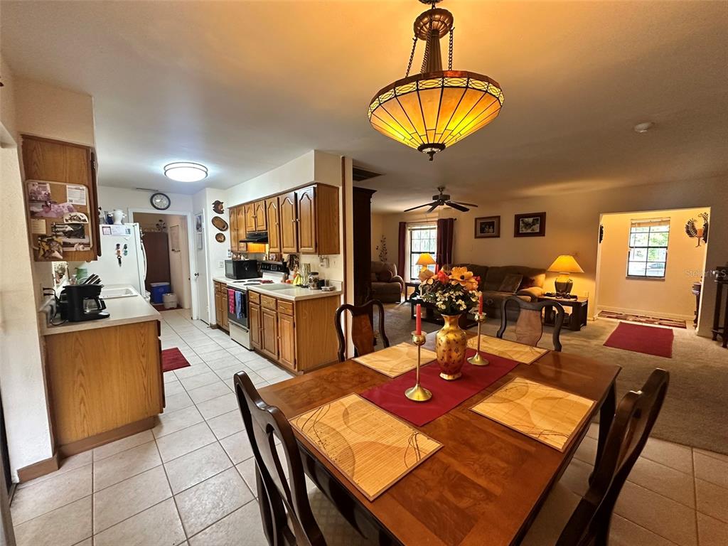 A dining area with a wooden table sits adjacent to a kitchen with oak cabinets — 5626 STULL AVENUE, ORLANDO, FL