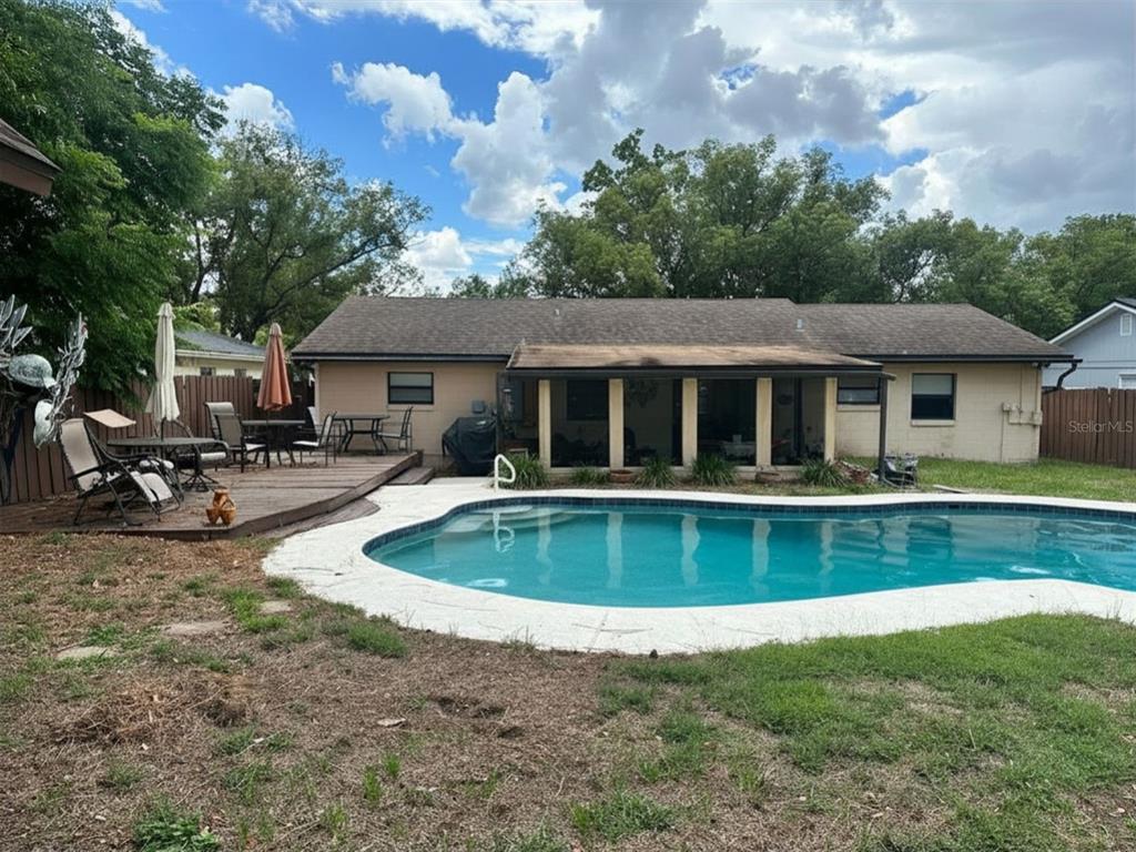 A backyard features a swimming pool, a wooden deck with patio furniture, and a house — 5626 STULL AVENUE, ORLANDO, FL