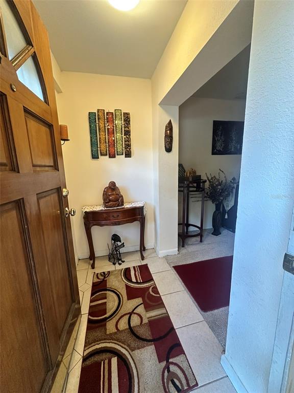 An entryway features a wooden door, a console table with a statue, and tiled flooring — 5626 STULL AVENUE, ORLANDO, FL