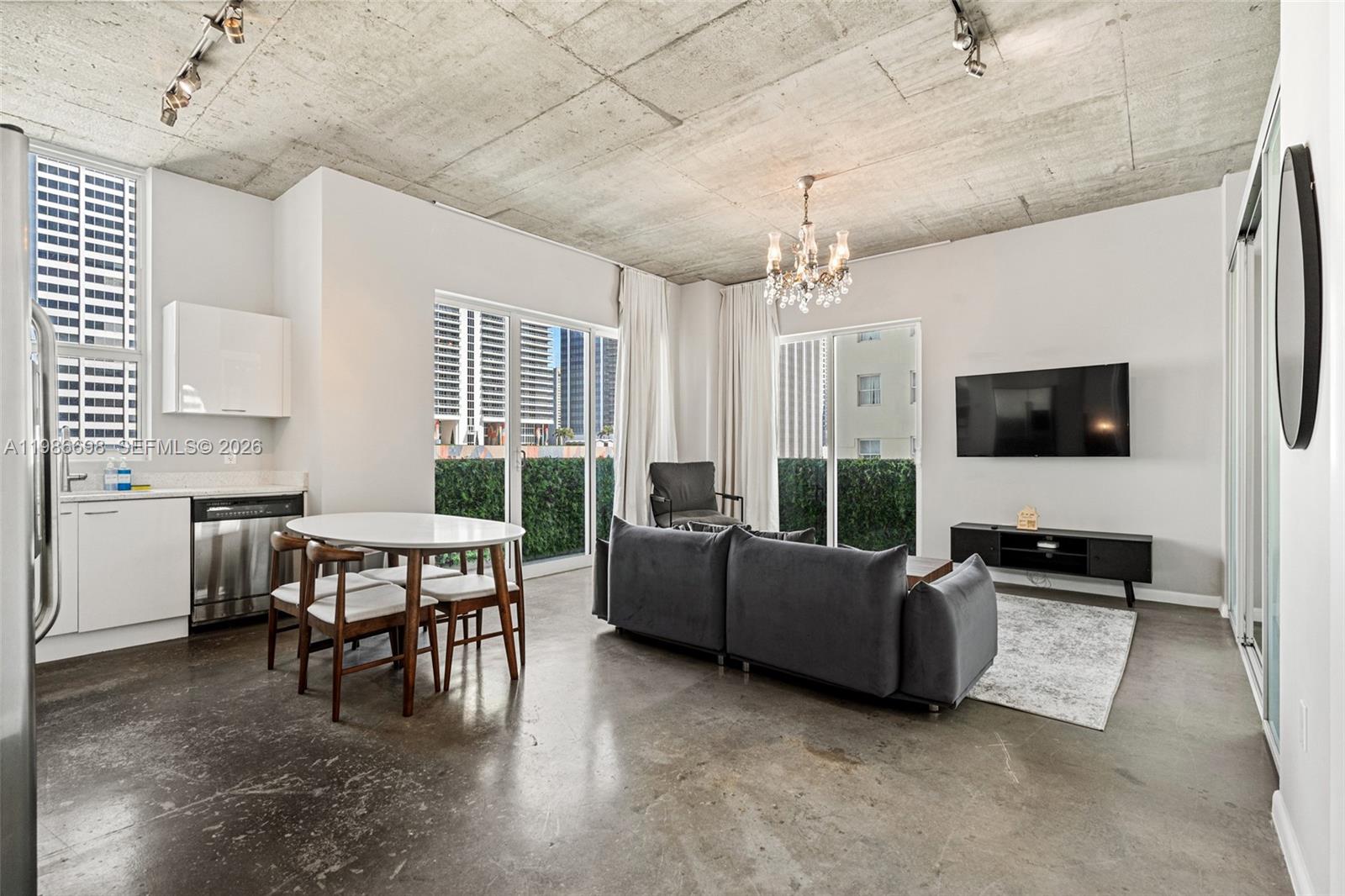An open-concept living room features a concrete ceiling, polished concrete floors, and a modern kitchen — 133 NE 2nd Ave # 912, Miami FL 33132, MIAMI, FL