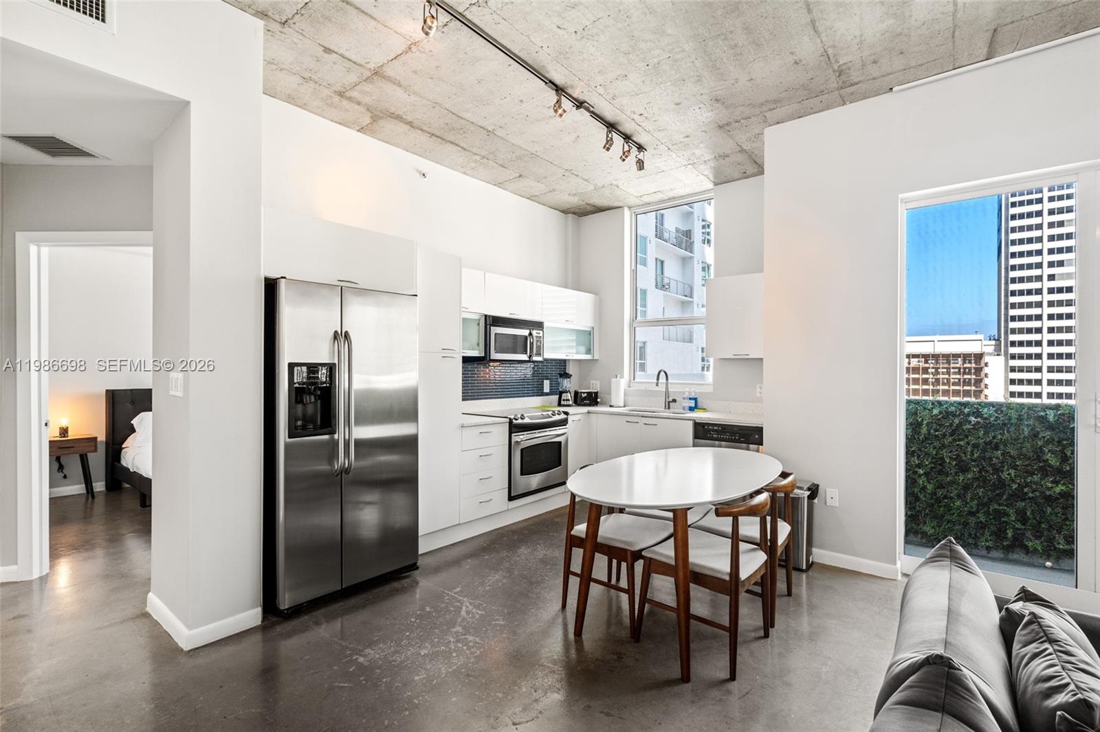 A modern kitchen with concrete ceilings, stainless steel appliances, and a dining table — 133 NE 2nd Ave # 912, Miami FL 33132, MIAMI, FL