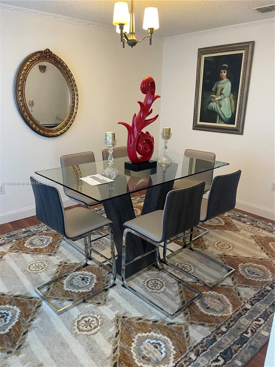 A dining room features a glass-topped table, six modern chairs, and a patterned area rug — 2645 SW 12th Sq SW, Vero Beach FL 32968, VERO BEACH, FL