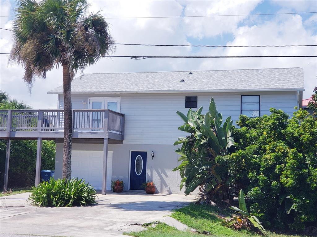 A two-story house with a raised deck, a garage, and a dark blue front door — 6318 TURTLEMOUND ROAD, NEW SMYRNA BEACH, FL