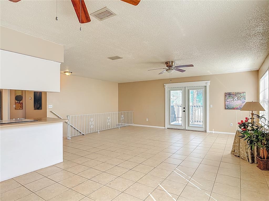 A spacious living area with tile flooring, a ceiling fan, and a white metal railing — 6318 TURTLEMOUND ROAD, NEW SMYRNA BEACH, FL