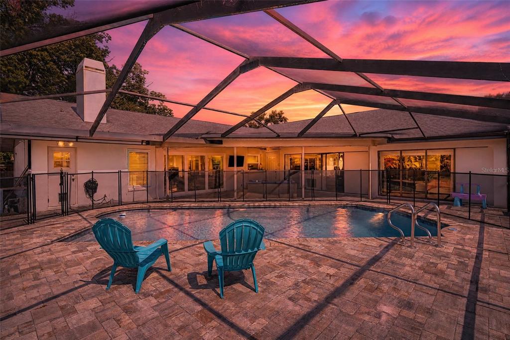 A backyard swimming pool with a screen enclosure and two turquoise chairs on a patio — 2717 REDFORD COURT E, CLEARWATER, FL