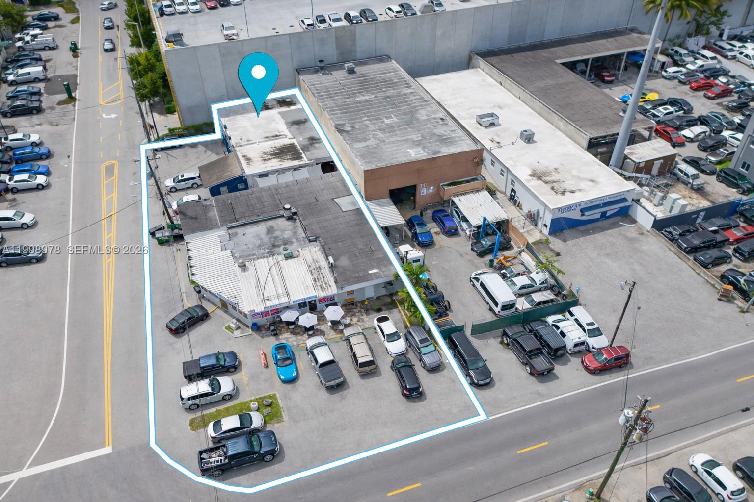 An aerial view shows a commercial property with a building, parking lot, and surrounding vehicles — 3300 NW South River Dr, Miami FL 33142, MIAMI, FL
