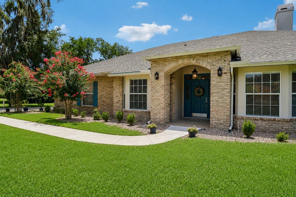 A brick house exterior features a blue front door under an arched entryway and landscaping — 1616 REGAL COVE COURT, KISSIMMEE, FL