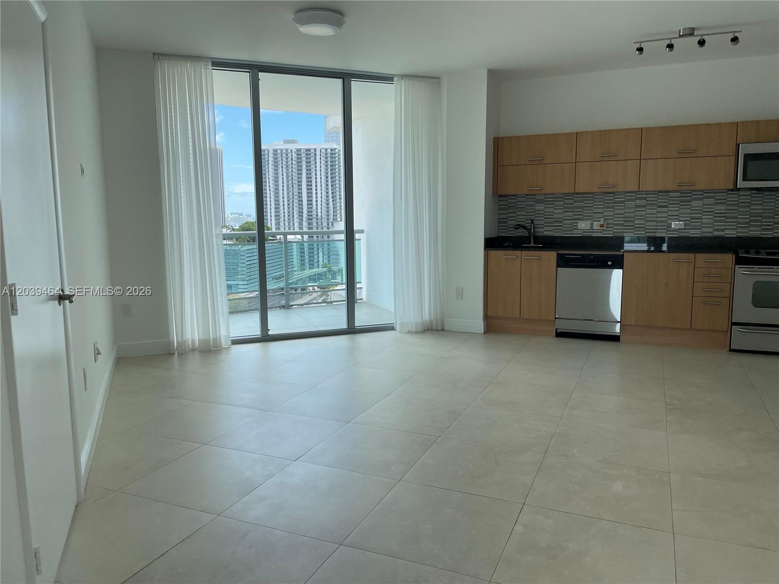 An open-concept kitchen and living area features light tile flooring and a balcony with city views — 350 S Miami Ave # 1913, Miami FL 33130, MIAMI, FL