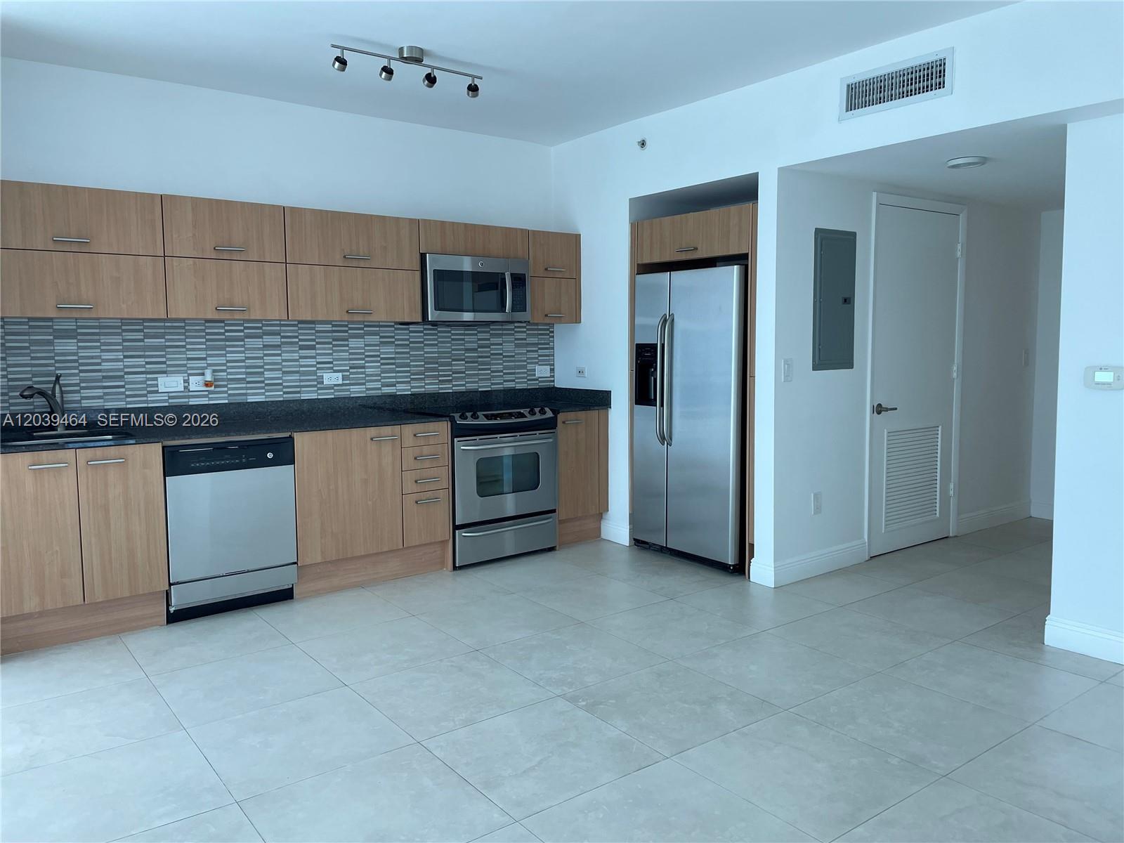 A modern kitchen features light wood cabinets, stainless steel appliances, and a tiled backsplash — 350 S Miami Ave # 1913, Miami FL 33130, MIAMI, FL