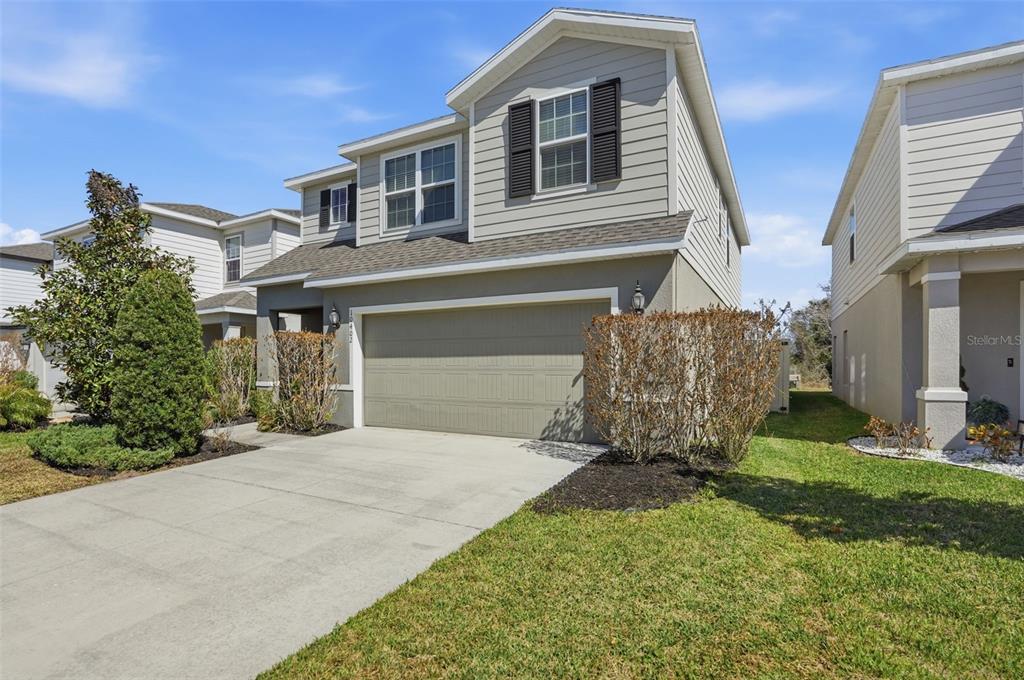 A two-story suburban house with light gray siding, a two-car garage, and a concrete driveway — 10402 HAWKS LANDING DRIVE, LAND O LAKES, FL