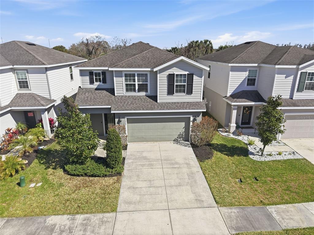 An aerial view of a two-story suburban house with a gray exterior and concrete driveway — 10402 HAWKS LANDING DRIVE, LAND O LAKES, FL