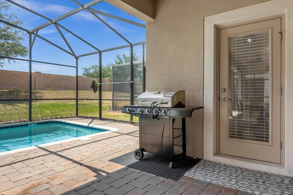 A covered patio features a grill, a small swimming pool, and a glass door entrance — 1483 ROLLING FAIRWAY DRIVE, CHAMPIONS GATE, FL
