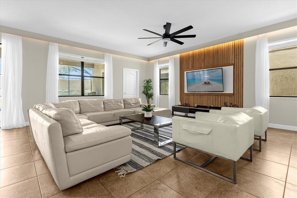 A living room features a large sectional sofa, two armchairs, and a wood-slatted accent wall — 1483 ROLLING FAIRWAY DRIVE, CHAMPIONS GATE, FL