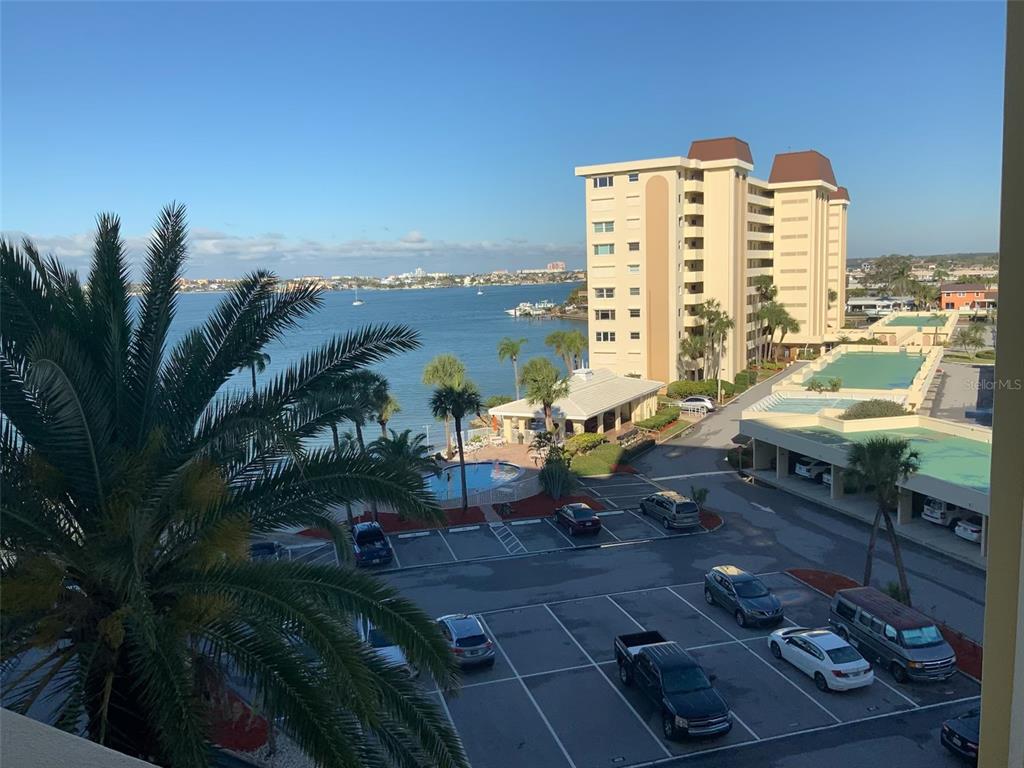 An elevated view of a parking lot, a swimming pool, and a high-rise building by water — 4575 COVE CIRCLE UNIT 703, ST PETERSBURG, FL