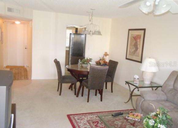 A dining area with a round table and four chairs sits adjacent to a living room — 4575 COVE CIRCLE UNIT 703, ST PETERSBURG, FL