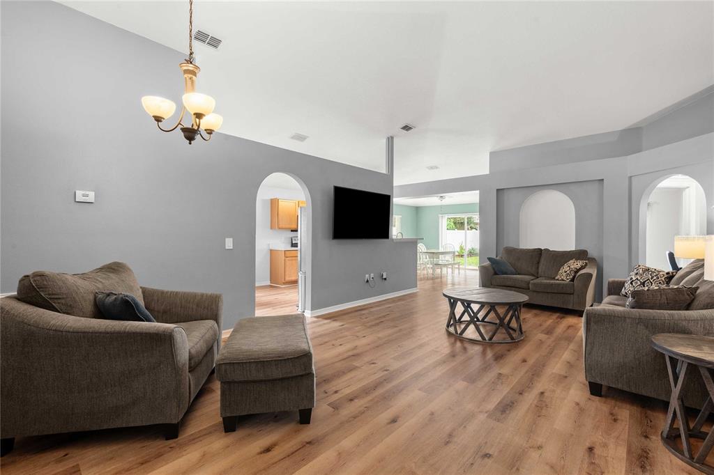 A living room with gray walls, wood-look flooring, a vaulted ceiling, and arched doorways — 14423 FINSBURY DRIVE, SPRING HILL, FL