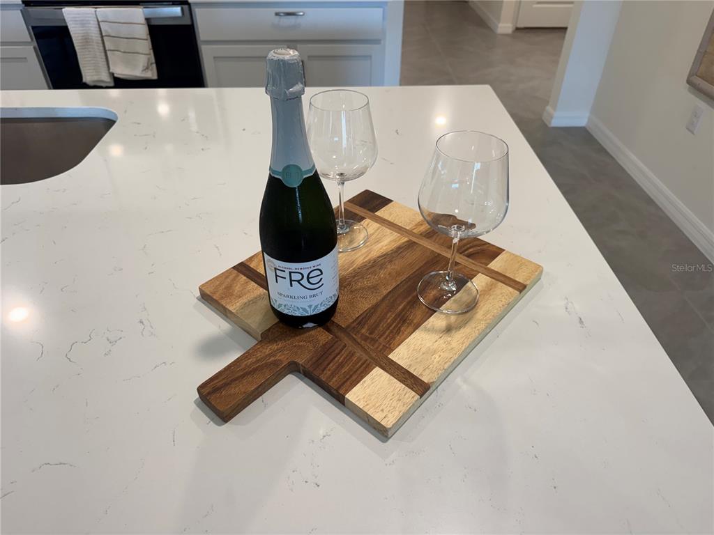 A bottle of sparkling wine and two glasses sit on a wooden cutting board — 16820 SW 29TH TERRACE ROAD, OCALA, FL