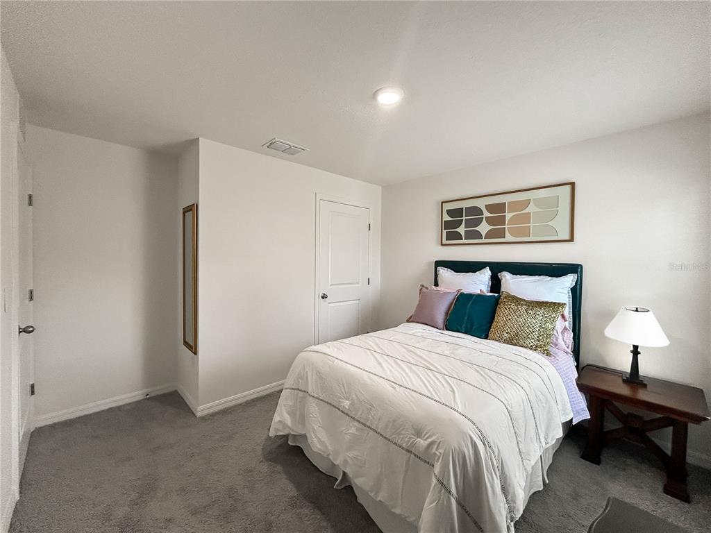 A bedroom features a bed with decorative pillows, a side table with a lamp, and carpet — 16820 SW 29TH TERRACE ROAD, OCALA, FL