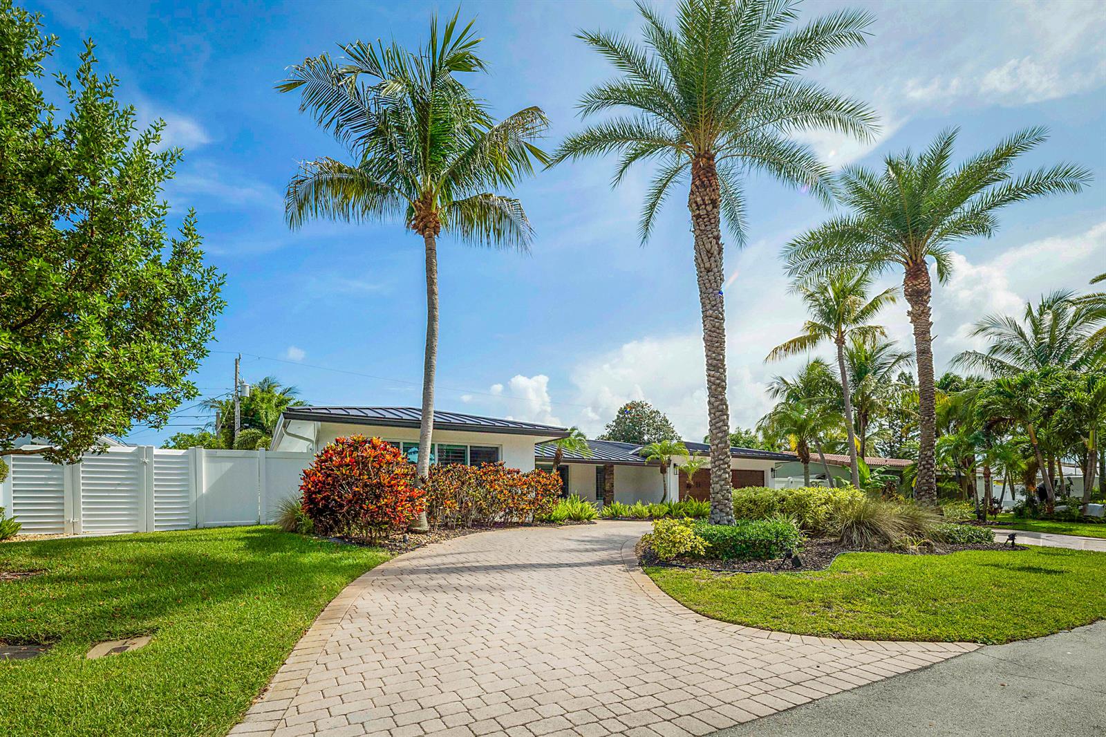 A paved driveway leads to a single-story house surrounded by palm trees and landscaping — 2620 NE 53rd Street, Lighthouse Point FL 33064, LIGHTHOUSE POINT, FL