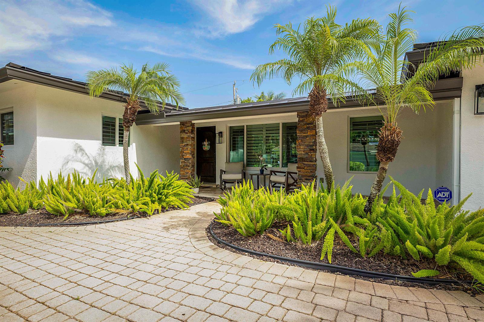 The exterior of a single-story house features a stone-accented entryway, palm trees, and landscaping — 2620 NE 53rd Street, Lighthouse Point FL 33064, LIGHTHOUSE POINT, FL