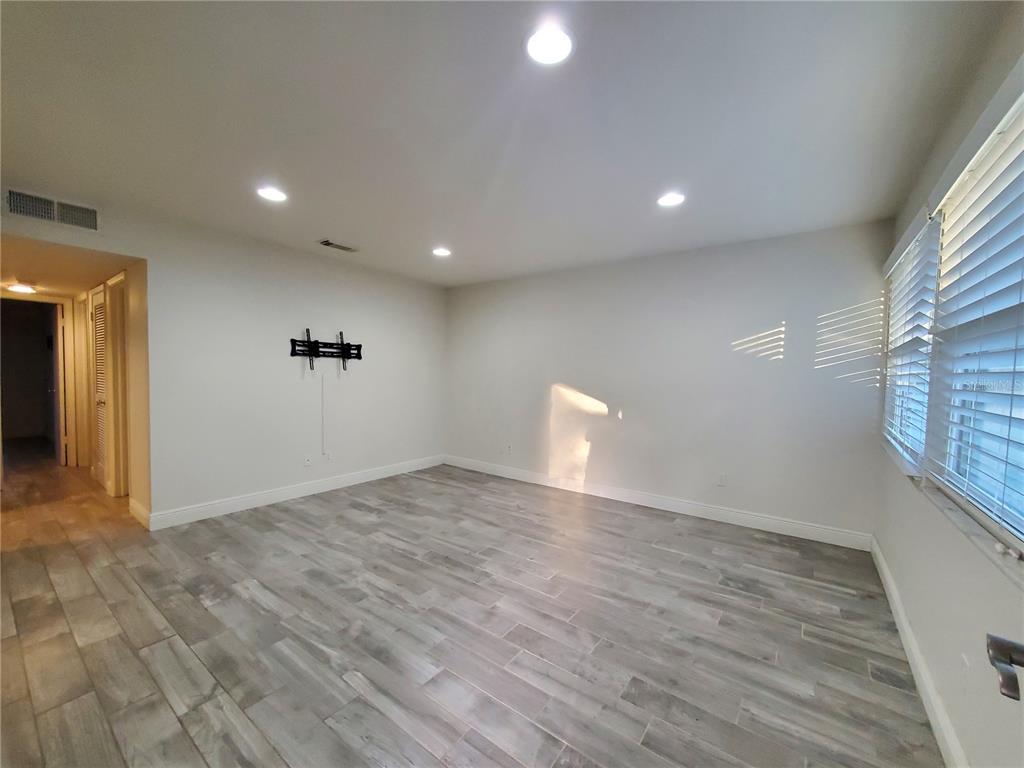 An empty room with gray wood-look tile flooring, white walls, recessed lighting, and a wall-mounted bracket — 3107 W HORATIO STREET UNIT B22, TAMPA, FL