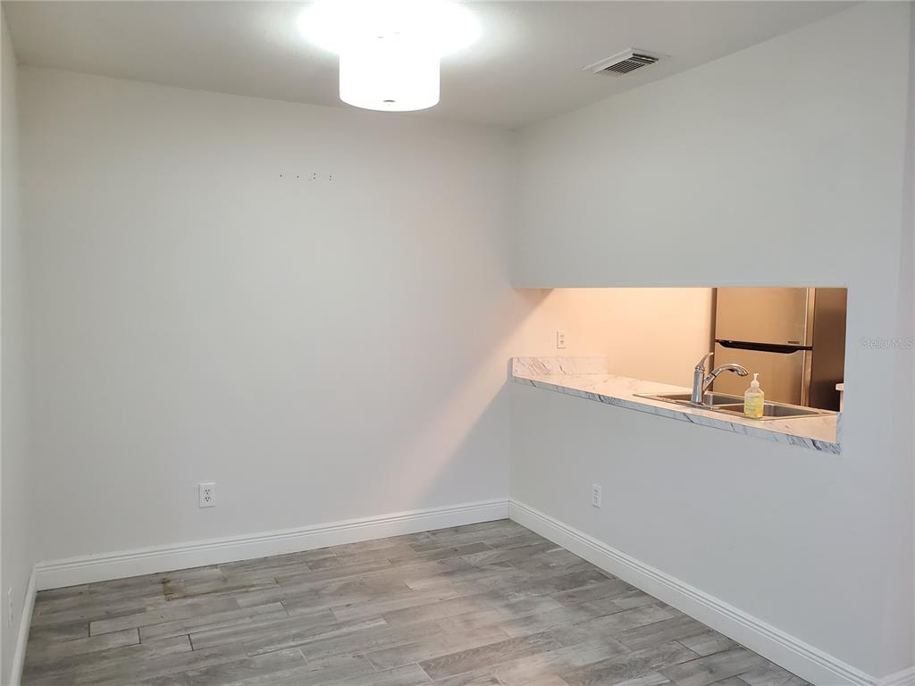 A dining area with gray wood-look flooring, a pendant light, and a kitchen pass-through window — 3107 W HORATIO STREET UNIT B22, TAMPA, FL