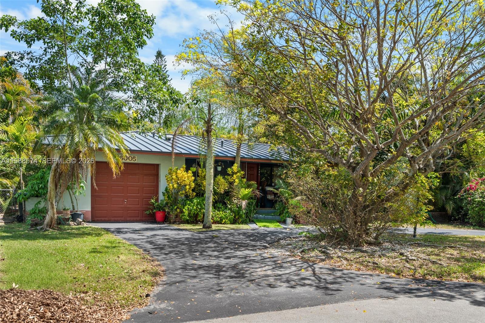 A single-story house with a metal roof, a garage, and lush landscaping — 6005 SW 64th Pl, South Miami FL 33143, SOUTH MIAMI, FL