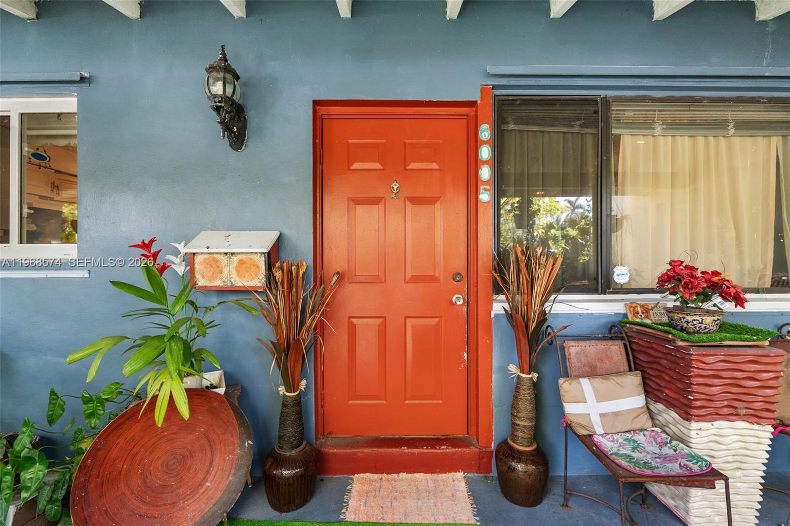 A blue exterior wall features a bright orange front door flanked by decorative potted plants — 6005 SW 64th Pl, South Miami FL 33143, SOUTH MIAMI, FL