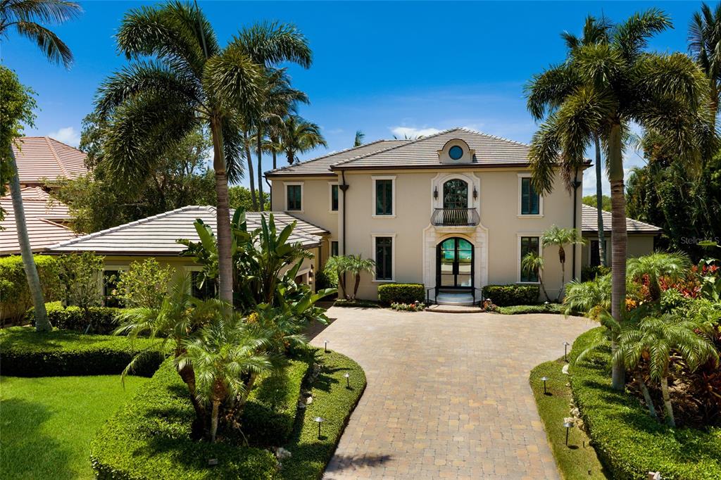 A two-story beige house with a tiled roof, arched entryway, and a paved driveway — 65 LIGHTHOUSE POINT DRIVE, LONGBOAT KEY, FL