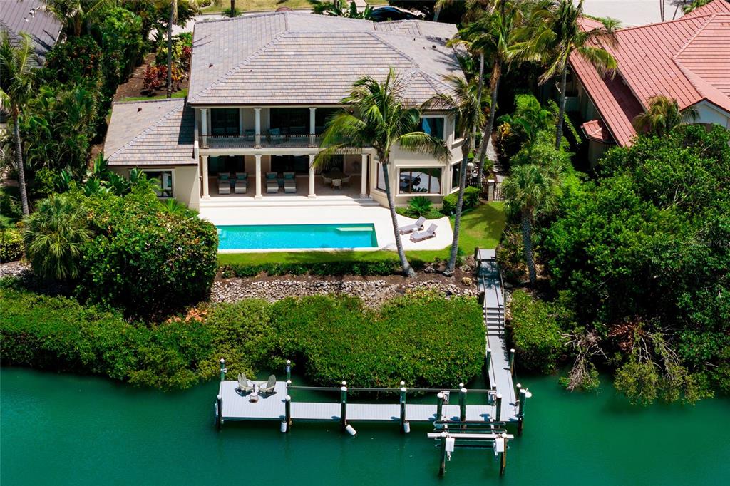 An aerial view of a waterfront house with a swimming pool, patio, and private dock — 65 LIGHTHOUSE POINT DRIVE, LONGBOAT KEY, FL