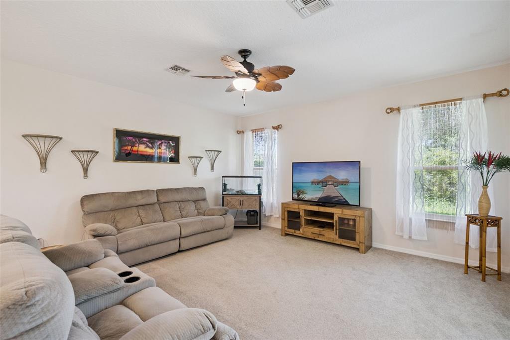 A living room features a grey sofa, a wooden media console, and a ceiling fan — 2589 CORBYTON COURT, ORLANDO, FL