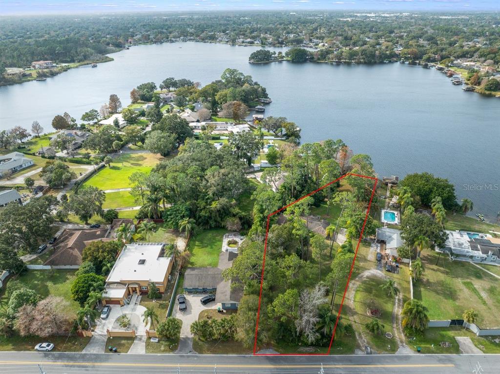 An aerial view shows a wooded residential lot outlined in red next to a lake — 3658 N ECONLOCKHATCHEE TRAIL, ORLANDO, FL