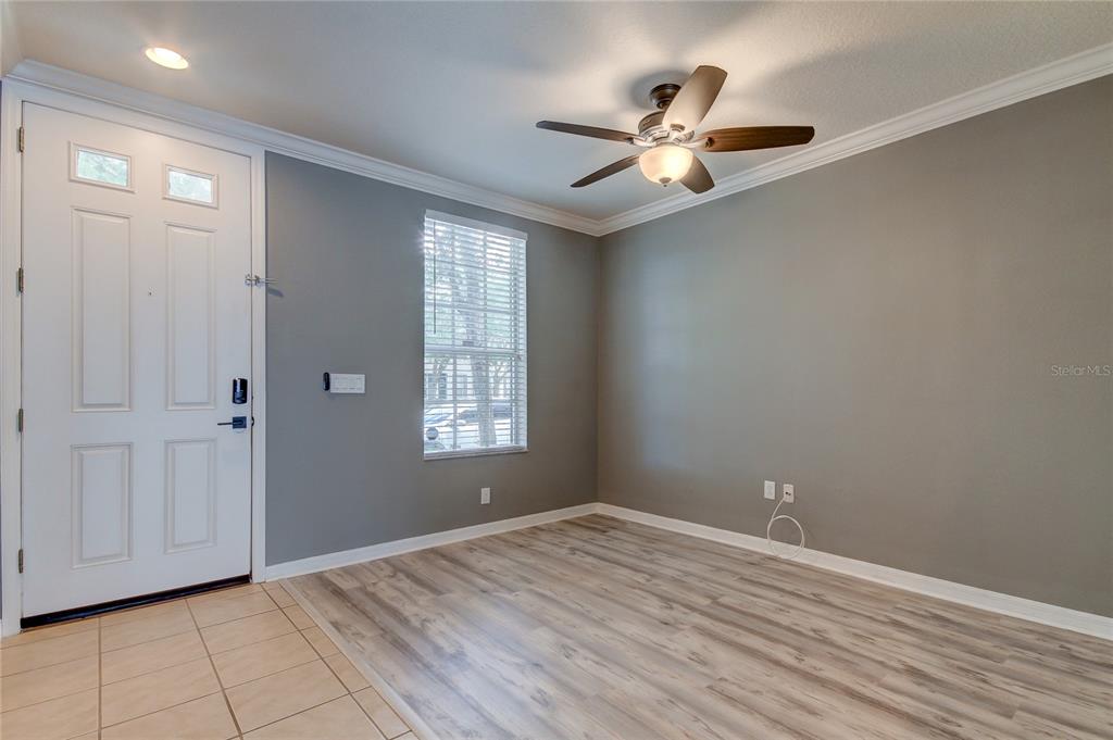A room with gray walls, wood-look flooring, a ceiling fan, and a white front door — 10003 BRADWELL PLACE, TAMPA, FL