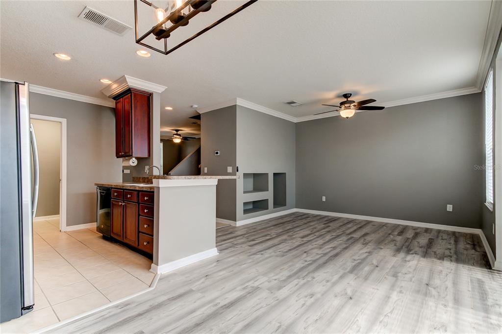 A kitchen with dark wood cabinets and a breakfast bar opens into a gray living area — 10003 BRADWELL PLACE, TAMPA, FL