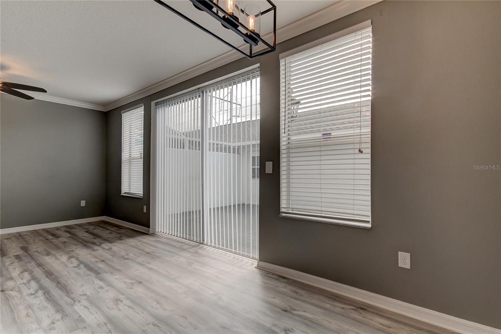 A room with gray walls, wood-look flooring, a sliding glass door, and window blinds — 10003 BRADWELL PLACE, TAMPA, FL