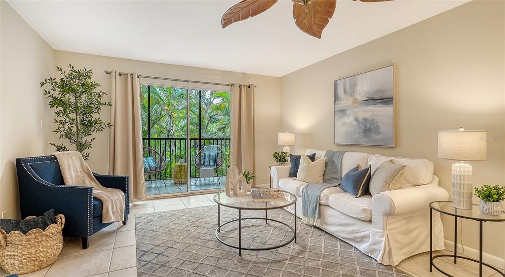 A living room features a white sofa, a blue armchair, and a sliding door to a balcony — 3700 S OSPREY AVENUE UNIT 222, SARASOTA, FL