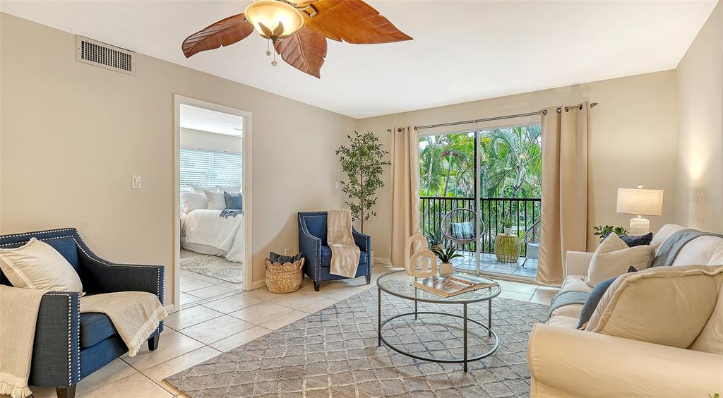 A living room features tile floors, a blue armchair, a white sofa, and a balcony view — 3700 S OSPREY AVENUE UNIT 222, SARASOTA, FL