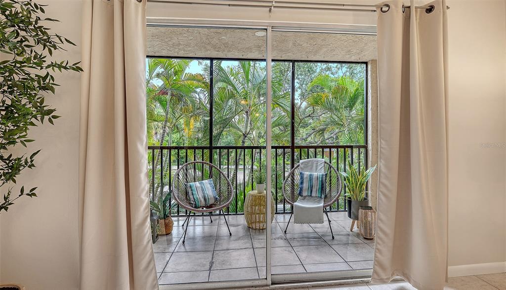 A view through a sliding glass door shows a screened-in balcony with two chairs — 3700 S OSPREY AVENUE UNIT 222, SARASOTA, FL