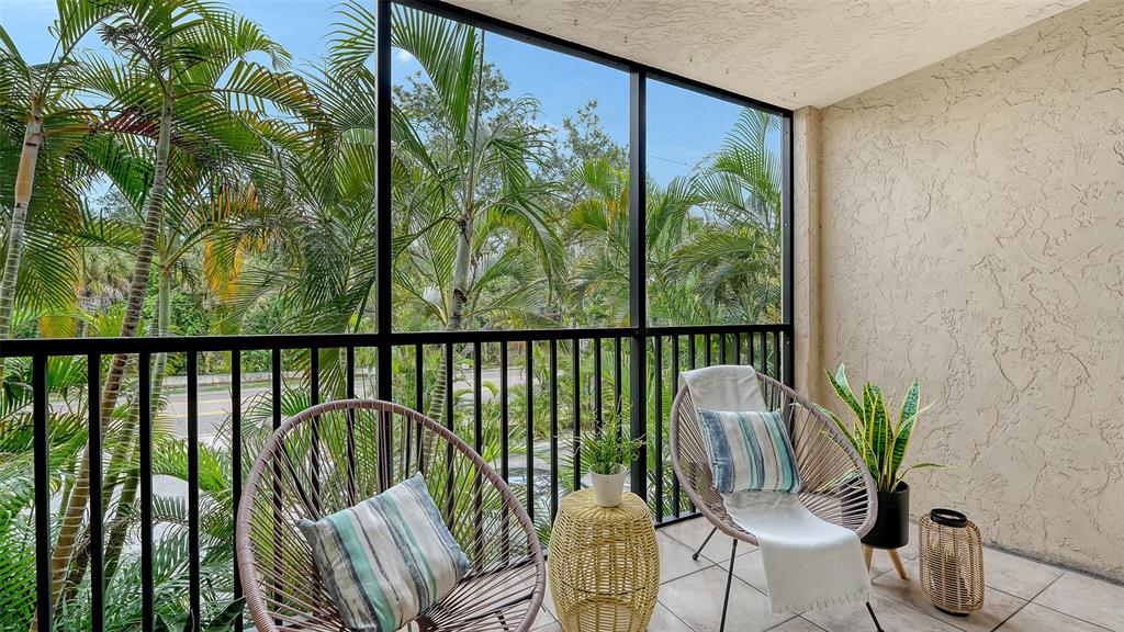 A screened-in balcony features two woven chairs, a small side table, and potted plants — 3700 S OSPREY AVENUE UNIT 222, SARASOTA, FL