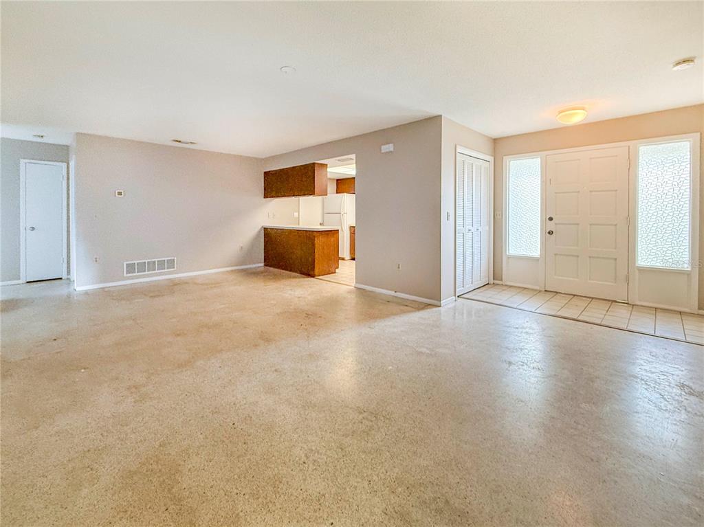 An open-concept living area features concrete floors, a kitchen pass-through, and a front entryway — 4417 PARNELL DRIVE, SARASOTA, FL