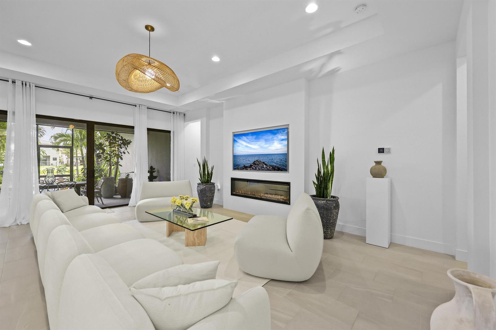 A modern living room features white furniture, a fireplace, a television, and a glass door — 17044 Watersprite Lakes Road, Boca Raton FL 33496, BOCA RATON, FL
