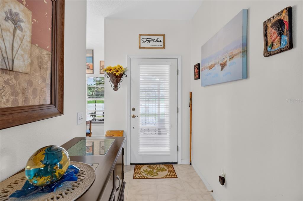 A bright entryway features a white front door, tiled floors, and various wall art pieces — 4188 ABERDEEN LANE, LAKE WALES, FL